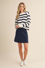 Model wearing a Striped SweaterTop with a mini skirt in navy, styled with white sneakers.
